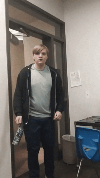 A Man Standing In A Doorway Holding A Water Bottle That Says ' I 'M Sorry ' On It GIF