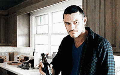 A Man Standing In A Kitchen Holding A Bottle GIF