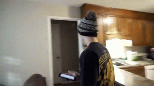 A Man Standing In A Kitchen Wearing A Black Shirt That Says Release GIF