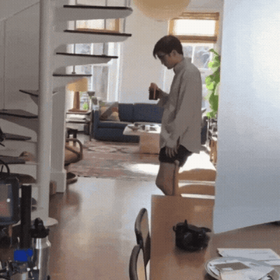 A Man Standing In A Living Room Holding A Bottle GIF