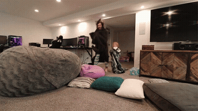 A Man Standing In A Living Room With A Large Bean Bag Chair GIF