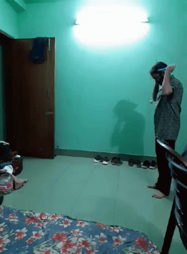 A Man Standing In A Room With A Floral Blanket On The Floor GIF