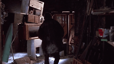 A Man Standing In A Room With A Stack Of Appliances GIF