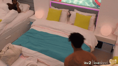 A Man Standing In Front Of A Bed That Says Itv2 Love Island GIF