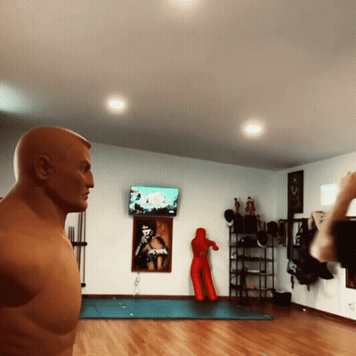 A Man Standing In Front Of A Boxing Dummy In A Room GIF