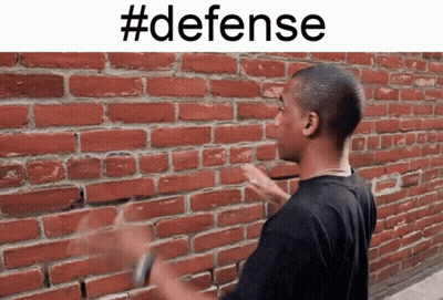 A Man Standing In Front Of A Brick Wall With #Defense Written Above Him GIF