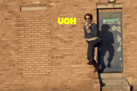 A Man Standing In Front Of A Brick Wall With The Word Ugh Written On It GIF
