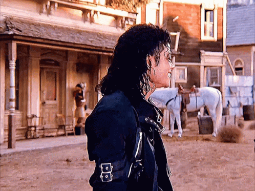 A Man Standing In Front Of A Building With A White Horse GIF