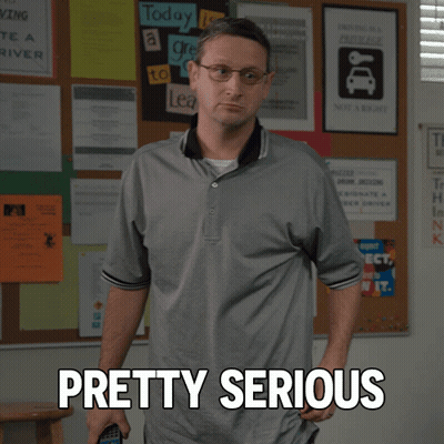 A Man Standing In Front Of A Bulletin Board With Pretty Serious Written On It GIF