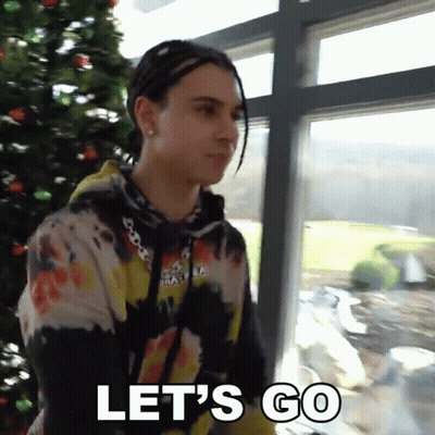 A Man Standing In Front Of A Christmas Tree With The Words Let 'S Go Below Him GIF