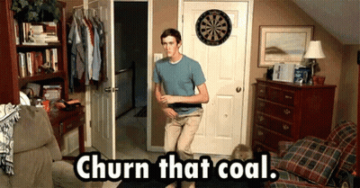 A Man Standing In Front Of A Dart Board With The Words Churn That Coal Written Below Him GIF
