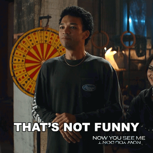 A Man Standing In Front Of A Dart Board With The Words That 'S Not Funny On The Bottom GIF