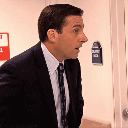 A Man Standing In Front Of A Delivery Room Sign GIF