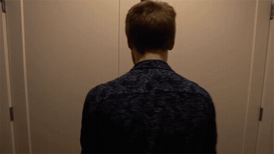 A Man Standing In Front Of A Door With His Back To The Camera GIF