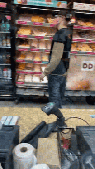 A Man Standing In Front Of A Dunkin Donuts Cooler GIF
