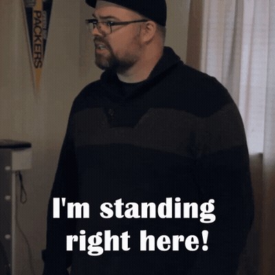 A Man Standing In Front Of A Green Bay Packers Banner That Says I 'M Standing Right Here GIF