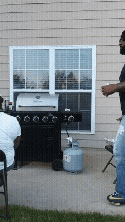 A Man Standing In Front Of A Grill With A Propane Tank In Front Of Him GIF