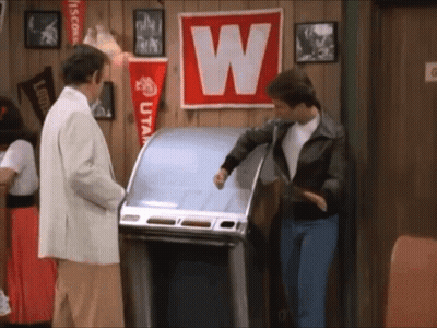 A Man Standing In Front Of A Jukebox With A W On It GIF