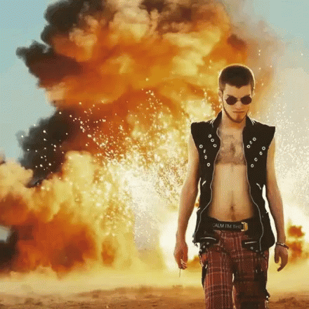 A Man Standing In Front Of A Large Explosion With The Word Calm On His Belt GIF