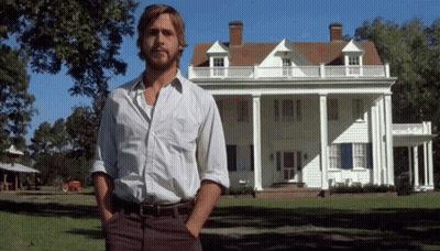 A Man Standing In Front Of A Large White House With His Hands In His Pockets GIF