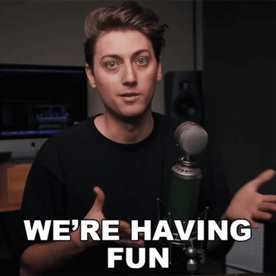 A Man Standing In Front Of A Microphone With The Words We 'Re Having Fun Above Him GIF