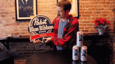 A Man Standing In Front Of A Pabst Blue Ribbon Sign GIF