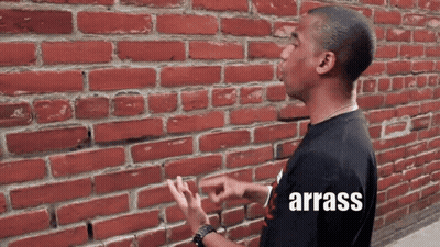 A Man Standing In Front Of A Red Brick Wall With The Word Arrass On The Bottom GIF