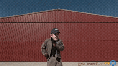 A Man Standing In Front Of A Red Building That Says Wutrade Clan On It GIF
