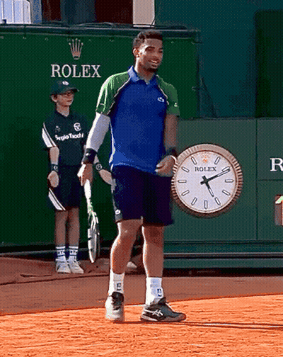 A Man Standing In Front Of A Rolex Clock GIF
