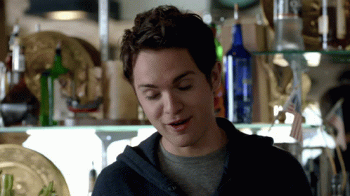 A Man Standing In Front Of A Shelf With A Bottle Of Vodka In It GIF