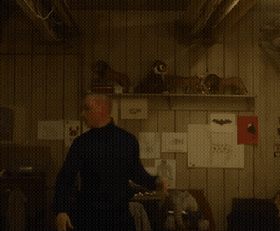 A Man Standing In Front Of A Shelf With Stuffed Animals GIF