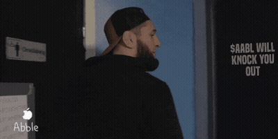 A Man Standing In Front Of A Sign That Says $ Aabll Will Knock You Out GIF