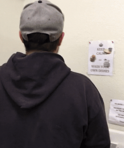 A Man Standing In Front Of A Sign That Says Keep Calm GIF