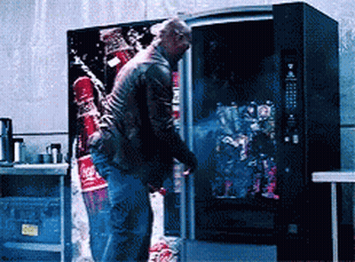 A Man Standing In Front Of A Vending Machine With A Coca Cola Advertisement On It GIF