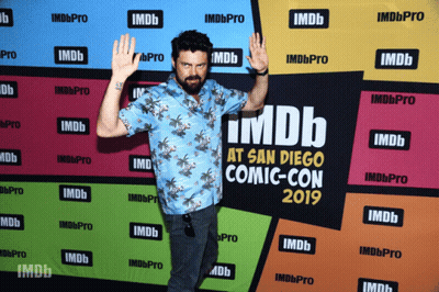 A Man Standing In Front Of A Wall That Says Imdb At San Diego Comic-Con 2019 GIF