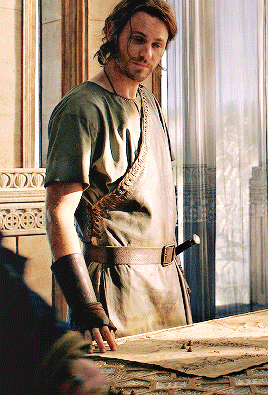 A Man Standing In Front Of A Window Wearing A Green Shirt And Brown Belt GIF