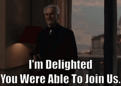 A Man Standing In Front Of A Window With The Words " I 'M Delighted You Were Able To Join Us " Written Below GIF