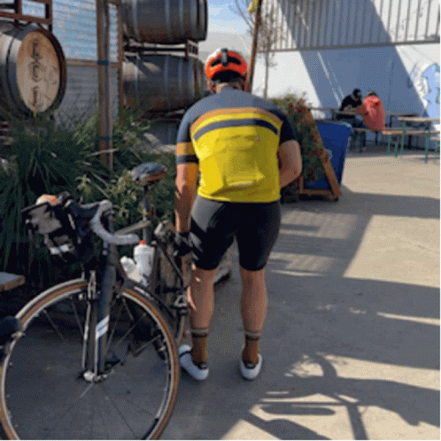 A Man Standing Next To A Bicycle Wearing A Yellow Shirt That Says ' Salomon ' On It GIF