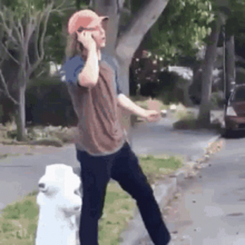 A Man Standing Next To A Fire Hydrant Talking On A Cell Phone . GIF