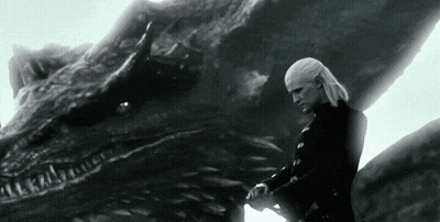A Man Standing Next To A Large Dragon With A Sword In His Hand GIF