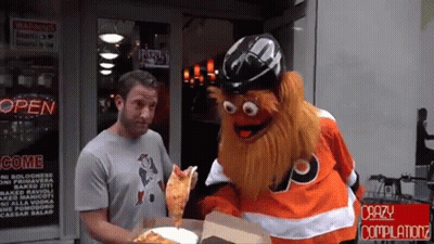 A Man Standing Next To A Mascot Holding A Pizza In Front Of A Store That Says Open GIF