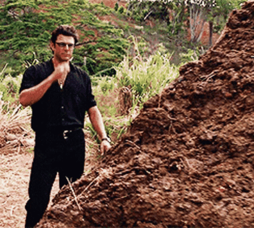 A Man Standing Next To A Pile Of Dirt GIF