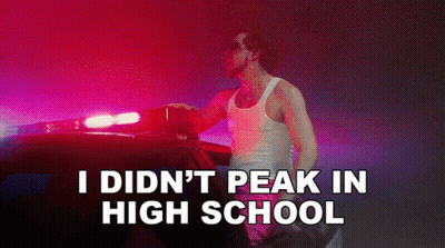 A Man Standing Next To A Police Car With The Words " I Did N't Peak In High School " On The Bottom GIF