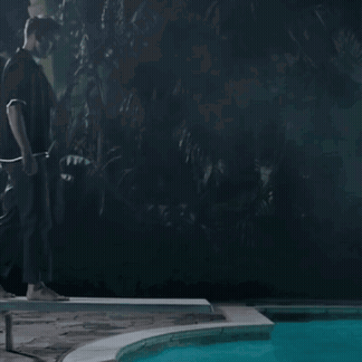 A Man Standing Next To A Pool At Night GIF