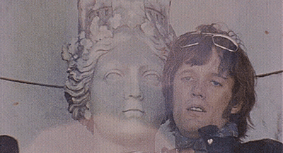 A Man Standing Next To A Statue With A Crown On His Head GIF
