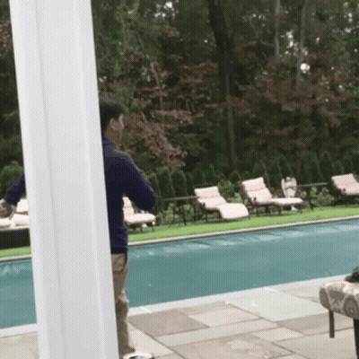 A Man Standing Next To A Swimming Pool Talking On His Phone GIF