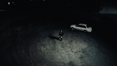 A Man Standing Next To A White Car In A Dark Parking Lot GIF
