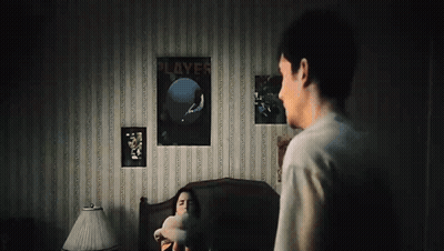 A Man Standing Next To A Woman In A Bedroom With A Poster On The Wall That Says " Players " GIF
