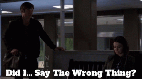 A Man Standing Next To A Woman With The Words Did I Say The Wrong Thing Behind Him GIF