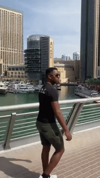 A Man Standing On A Bridge With A Building In The Background That Says Pier 7 On It GIF